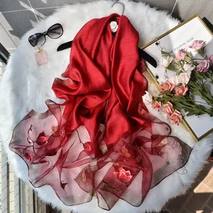 Elegant red silk scarf with floral butterfly embroidery on soft white plush background