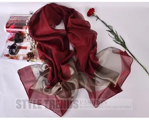 Detail of burgundy and gold silk organza shawl with fashion accessories on white backdrop