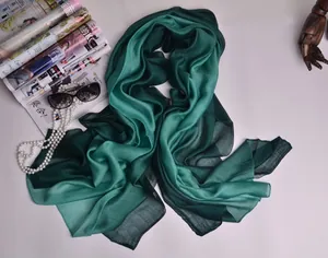 Detalle de bufanda de seda degradada con perlas y gafas sobre una revista de moda