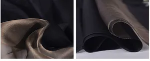 Macro detail of sheer silk scarf fabric with fine rolled edges in black and champagne gold