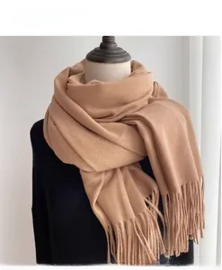 Detailed macro view of camel cashmere-feel winter scarf featuring classic tassel edges
