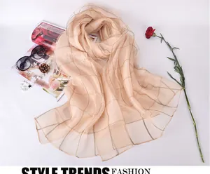 Detailed view of champagne silk scarf featuring a gold grid pattern with elegant accessories