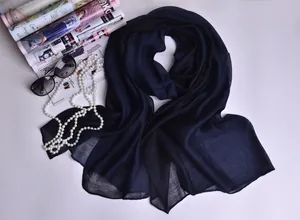 Detalle de la textura del pañuelo de seda azul marino con collar de perlas y revista