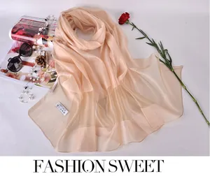 Close-up of champagne silk scarf with 100% silk label next to fashion accessories