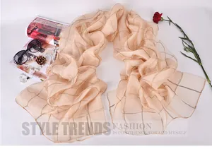 Close-up of light apricot silk scarf with golden grid patterns and fashion accessories