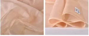 Macro shot of 100% silk fabric in soft pink showing texture and care label details
