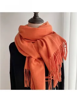 Close-up of bright orange pashmina scarf featuring detailed fringe tassels and soft texture