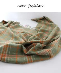 Close-up of green and orange houndstooth scarf showing soft fringe and fabric texture