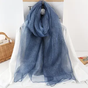 Detailed texture of navy blue silk scarf layered over white shirt with camellia flower decoration