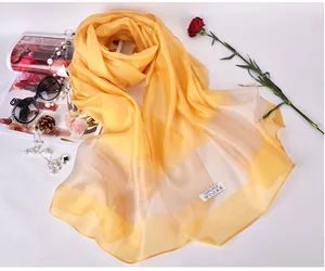 Detailed shot of yellow silk scarf showing the 100% silk label and soft material texture
