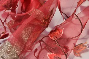 Detailed close-up of red silk scarf with gold floral embroidery and butterfly details