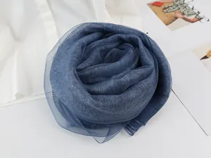 Detailed close-up of dark blue pleated silk scarf folded into a rose shape on a magazine