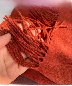 Close-up of orange cashmere scarf showing fine knit texture and neat fringe tassels