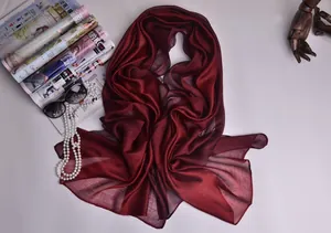 Detalle del pañuelo de seda burdeos con gafas de sol y collar de perlas elegantes