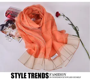 Detail of coral silk scarf featuring gold check pattern and organza pleated hem edge