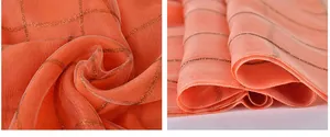 Close-up of salmon orange silk scarf featuring golden metallic square grid patterns