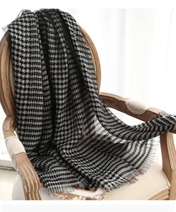 Detailed view of luxury silk houndstooth scarf with elegant fringe on a vintage wooden chair