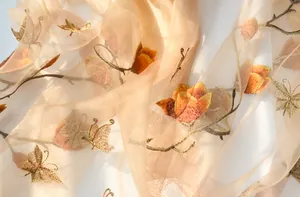 Detail of embroidered silk scarf featuring gold floral patterns and butterfly motifs