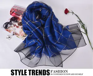 Detail of royal blue plaid silk scarf with gold threads and black mesh border on white background