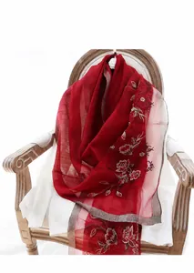 Primer plano de un chal de seda y lana rojo con bordados florales blancos detallados