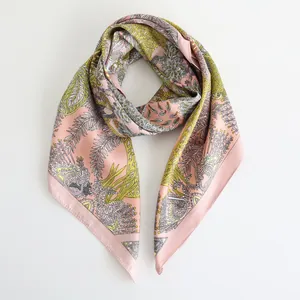 Elegante foulard in seta rosa piegato con motivi paisley verdi e bordo geometrico