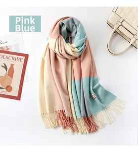 Detailed flat lay of pink and blue plaid wool scarf featuring soft tassels and fringe