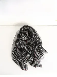 Detail of silk houndstooth scarf featuring red accents, fringe edges and mesh overlay