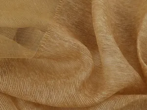 Macro detail of amber gold pleated silk scarf fabric showing light sheer texture