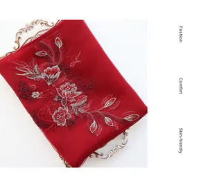 Detail of red silk wool scarf with intricate floral embroidery on a vintage tray