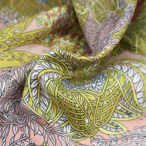 Dettaglio macro di un foulard in seta twill con stampe botaniche e morbide pieghe di tessuto