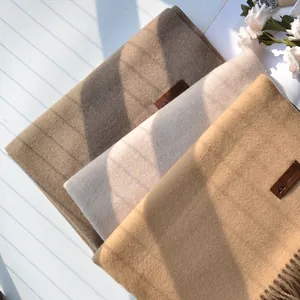 Detail shot of solid color cashmere-like scarves with tassel fringes and leather labels