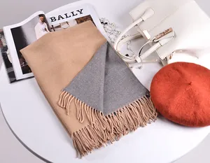 Dettaglio della sciarpa in cashmere reversibile grigio e cammello con nappe morbide
