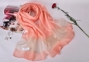 Detailed view of peach pink 100% silk scarf with official care label and premium texture