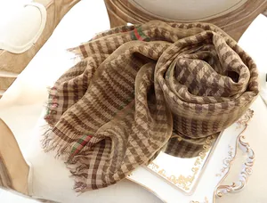 Detail of silk scarf with houndstooth pattern and fringe edges on a white tray