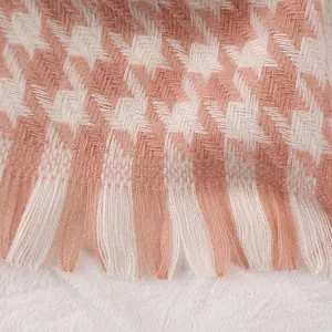 Close-up detail of soft pink and beige houndstooth scarf with classic tassel edges