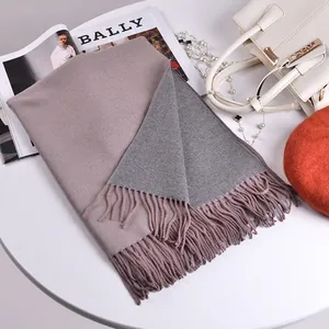 Dettaglio di sciarpa in cashmere rosa e grigio con frange su un tavolo di moda