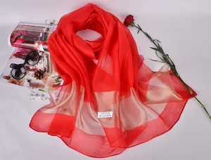 Detail of 100% silk scarf with red and gold stripes alongside fashion accessories