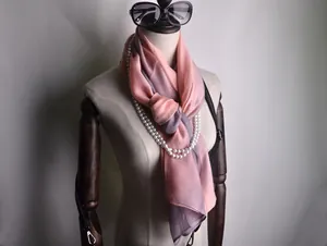 Detalle de bufanda de seda con degradado rosa y violeta decorada con collar de perlas fina