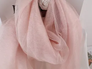 Detail of light pink pleated mulberry silk scarf with delicate layering and soft texture