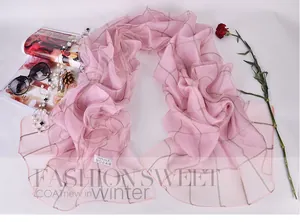 Macro shot of pink silk scarf showing 100% silk label and golden grid pattern