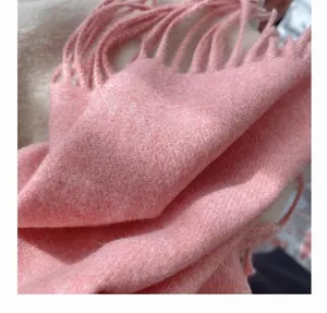Close-up detail of soft coral pink winter scarf with premium cashmere feel and fringe