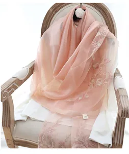 Detail view of peach silk wool scarf with delicate floral embroidery on a classic chair