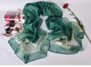 Close-up of green silk scarf with wash label showing 100% silk material and texture