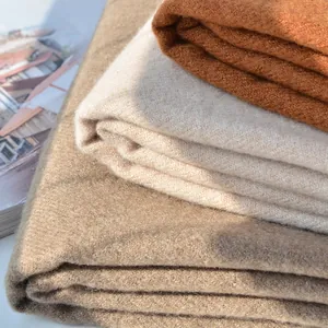 Detail shot of solid color cashmere-feel scarves in camel, beige, and caramel colors
