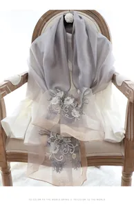 Detail of silk wool scarf showing floral embroidery on a gradient purple and beige fabric