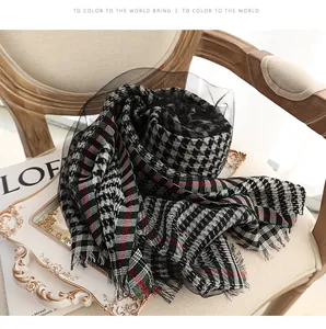 Classic houndstooth silk scarf with fringe detail on a vintage wooden armchair