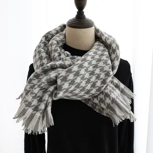 Detail of gray and white houndstooth scarf with soft fringe tassels for winter warmth