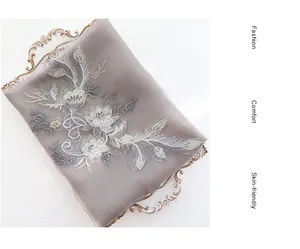 Detail of embroidered floral patterns on a luxury silk wool scarf in grey and gold