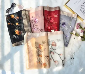 Detail of embroidered silk scarves with floral patterns and shimmering metallic edges