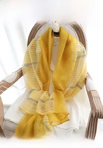Detail of yellow silk wool scarf with white stripes draped on a vintage chair
